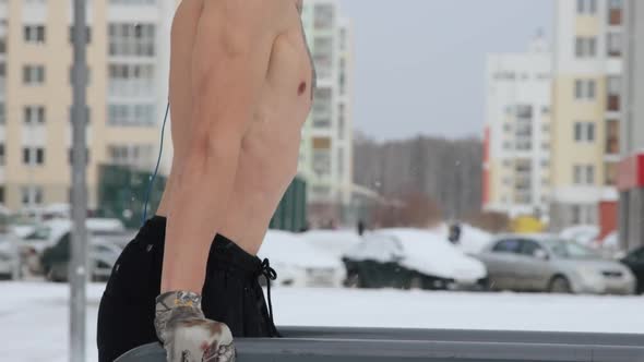 Muscular man training topless on sports field in winter