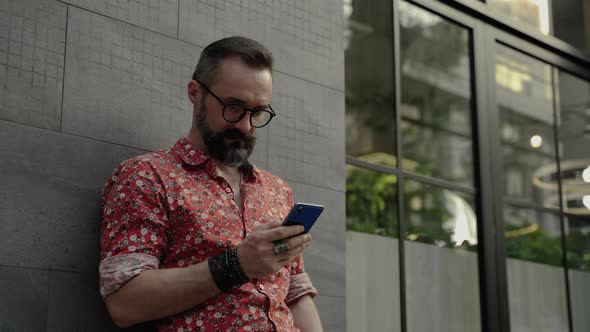 hipster man is using his mobile phone to keep in touch with his friends on social media. internet of