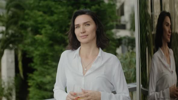 Young Beautiful Woman is Posing for Camera While Standing on Outdoors Balcony at House Rbbro alt