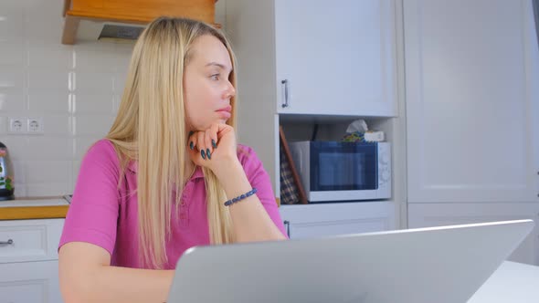 Freelancer woman in thought looking away in front of laptop computer alt