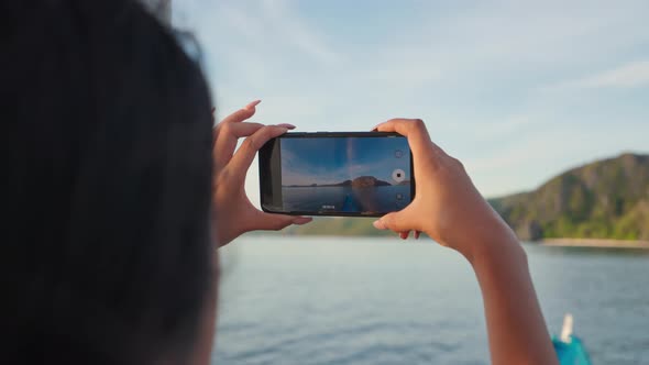 Woman Filming Helicopter Island From Boat On Smartphone alt