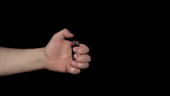A Man Is Trying To Light a Lighter. A Man Holds a Lighter in His Hand and Spins a Drum on a Black