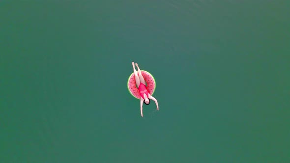 Overhead Top View of Woman Swimming with Watermelon Swimming Circle in Blue Water alt