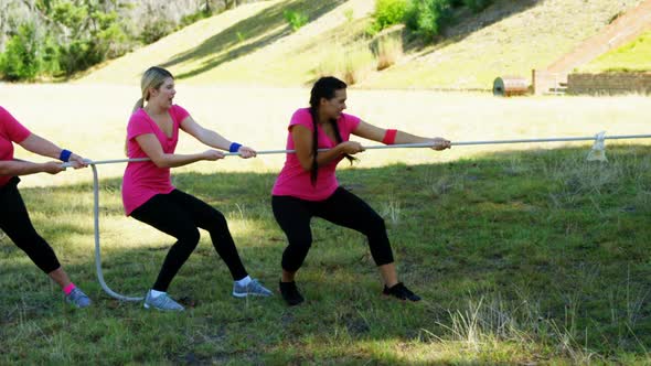 Group of women playing tug of war during obstacle course alt