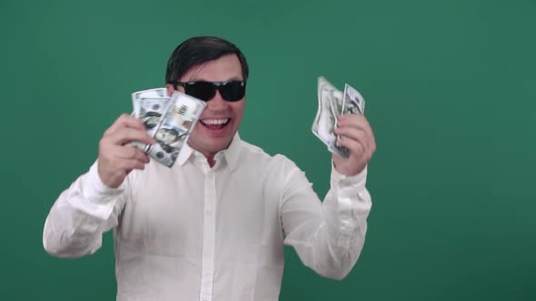 Cheerful man in sunglasses is smiling holding dollar bills. Slow motion