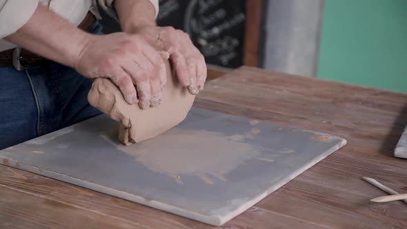 Adult Sculptor Working with Raw and Wet Clay in Workshop Room