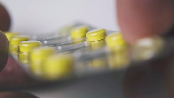 Person Shows Blister with Bright Pills on White Background alt