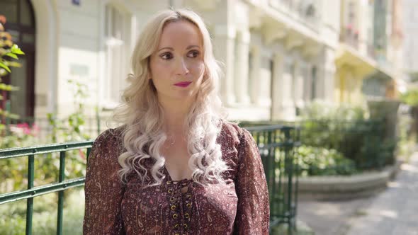 A Middleaged Caucasian Woman Acts Frustrated in an Urban Area  a City Street with Buildings alt