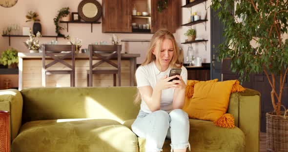 Young woman angrily texting into messages uses a mobile phone, gets angry alt