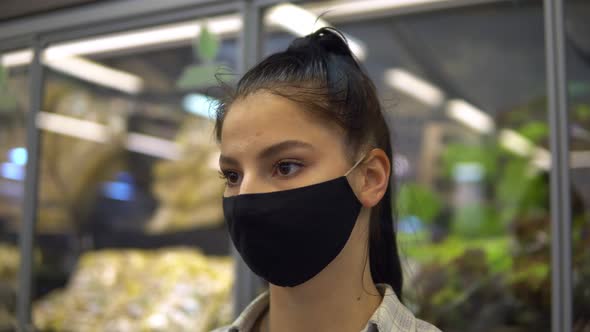 Woman in Supermarket in Protective Mask Looking on Shelves Choosing Products