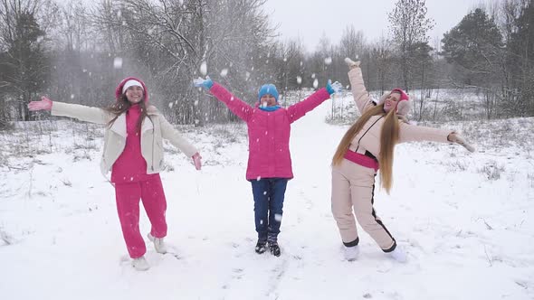 Three young women playing with snow outdoors in the forest