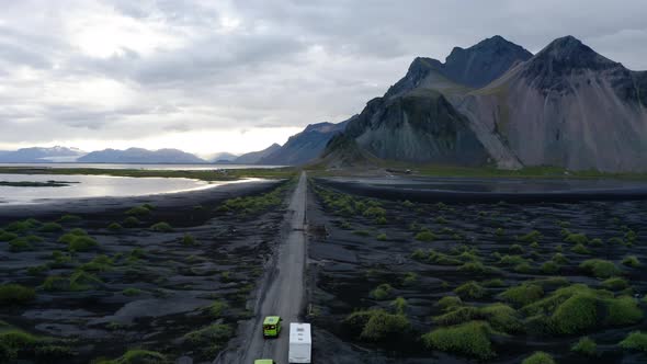 Vehicles Driving On The Road Passing Through Green Grass At Mount Vestrahorn alt