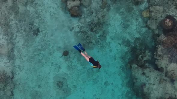 Aerial video of a girl exploring a tropical coral reef while snorkelling alt