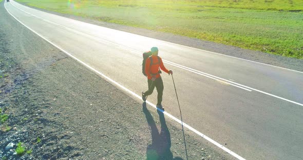 Flight Over Hitchhiker Tourist Walking on Asphalt Road. Huge Rural Valley at Summer Day. Backpack alt