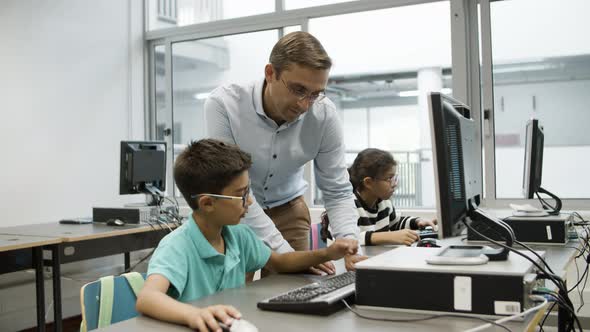 Cheerful Teacher and Schoolboy Working on Computer Together alt