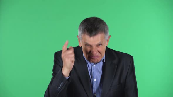Portrait of Aged Man Is Scolding, Shaking His Index Finger, Isolated Over Green Background. alt