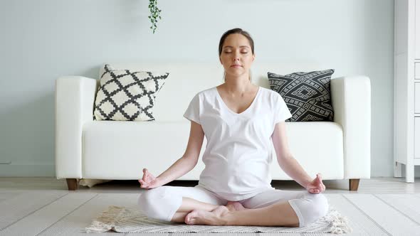 Tranquil Pregnant Woman Meditates in Lotus Pose at Home alt