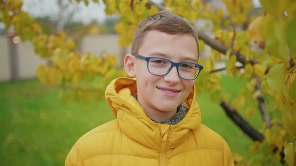 Close Up Smiling Boy in Reading Glasses Outdoors Yellow Foliage on Autumn Back alt