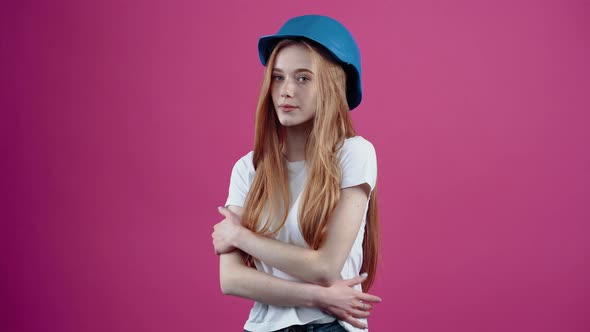 The Young Redhead Engineer with the Blue Helmet Puts Both Hands on Her Protector alt