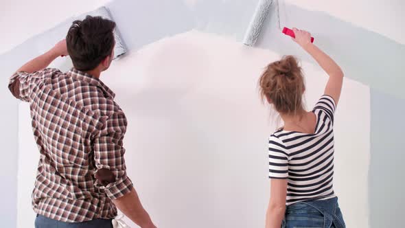 Young couple painting the interior wall in their new apartment  alt