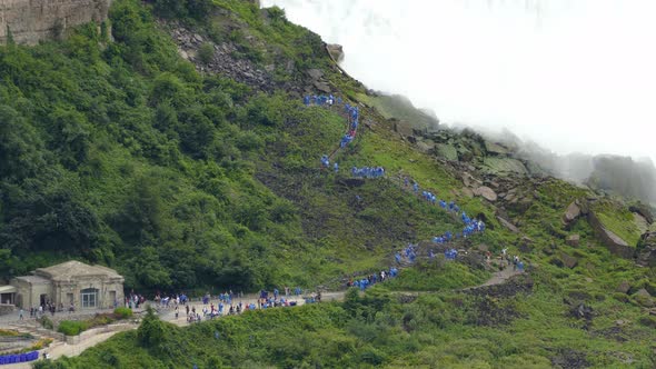 People in Blue Raincoat Climbing Stair Next to Niagara Falls, Establishing Shot alt