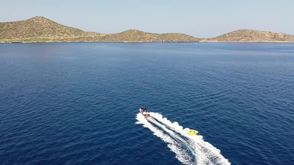 Aerial View of a Motor Boat Towing a Tube. Elounda, Crete, Greece