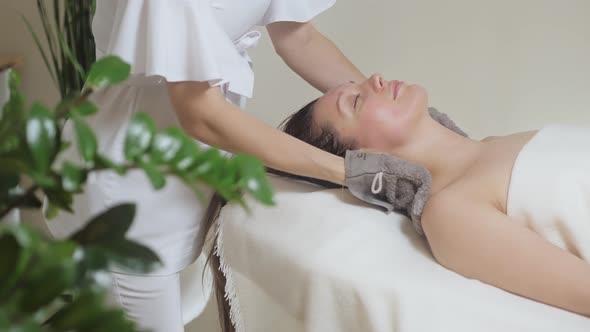 Beautiful Girl Lies in the Spa Salon and the Master Wipes Her with Special Glove alt