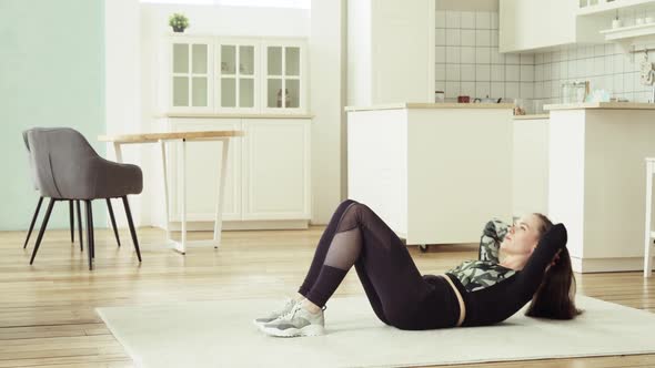 Young Woman Is Making Abdominal Exercises Crunches on Floor at Home, Side View.