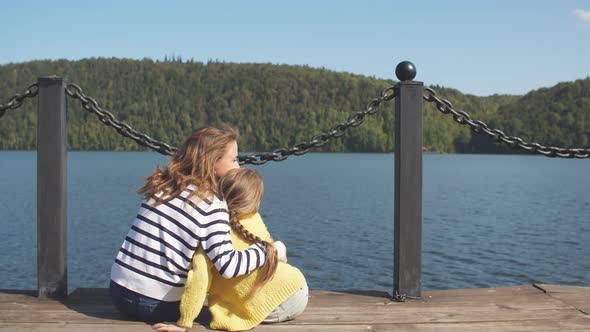 Mother and Daughter Sitting on Pier Warm Autumn Day alt