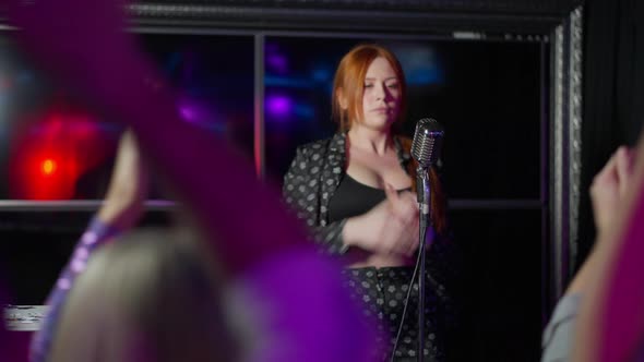 Joyful Talented Plussize Redhead Woman Clapping and Singing with Microphone on Stage As Crowd alt