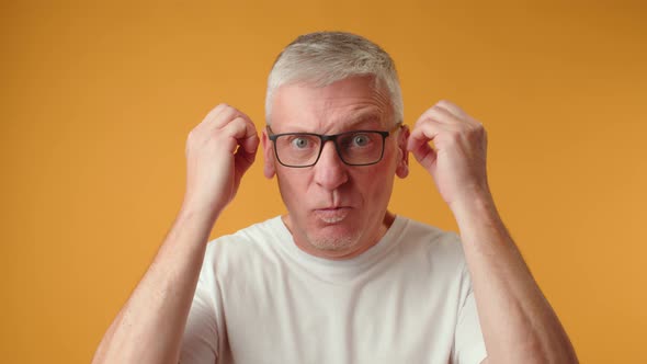 Senior Man with Exploding Head Gesture Against Yellow Background
