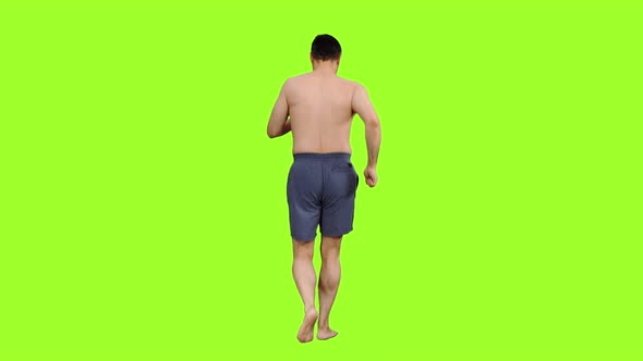 Rear View of Topless Man in Dark Shorts Jogging Barefoot 