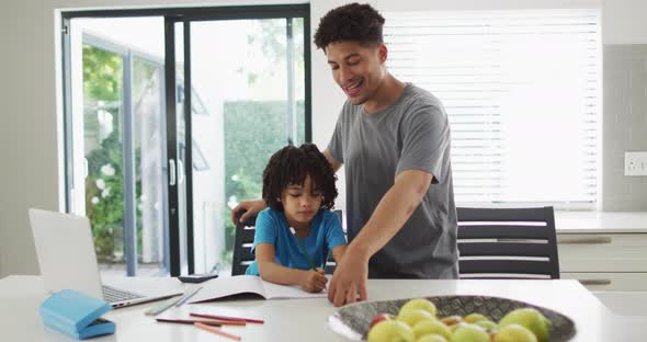 Happy biracial man and his son doing homework together alt