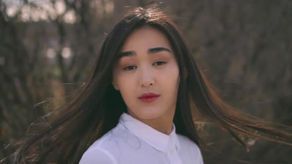 Beautiful Young Asian Girl Turning To Camera. Wind Gently Inflates Her Hair alt