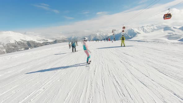 Woman Snowboarder on Snowboard Running Down the Slope in Ski Resort alt