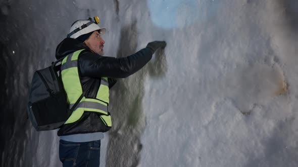 Confident Man Exploring Ice Cave with Snow Touching Walls Looking Around alt