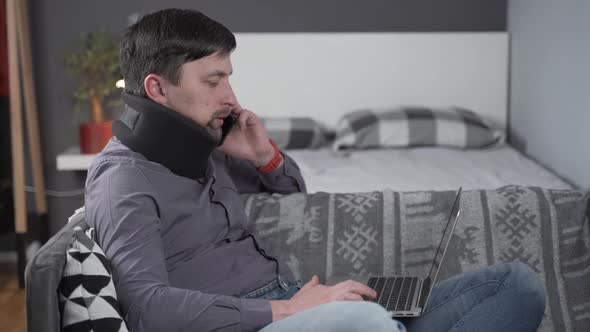 Man Employee After Accident Working at Home Behind Laptop and Calls the Doctor at Phone to Get alt