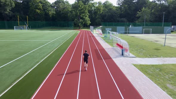 Man Running at Race Track at Stadium alt