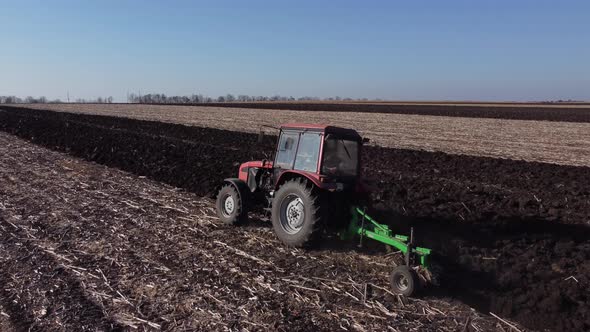 red tractor plows a field in autumn in Ukraine