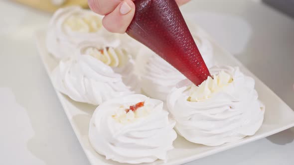 a Female Chef Adds Jam From a Pastry Bag to Anna Pavlova Cakes in the Kitchen alt