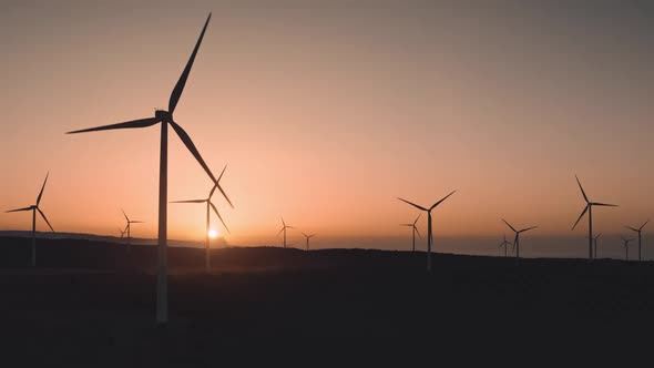 Windmills Turbines Generate Green Energy on Sunset in Suburban Countryside Area