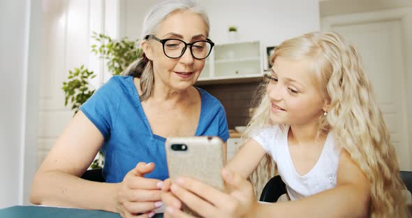 Grandmother and Granddaughter Scrolling Smartphone