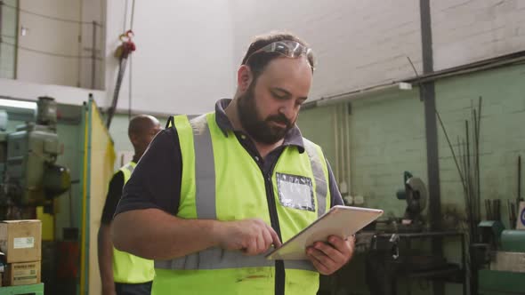 Caucasian male factory worker at a factory wearing a high vis vest alt