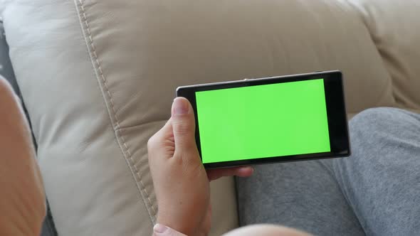 Woman scrolling pages on greenscreen smart phone display 4K 2160p UltraHD footage - Female holding c