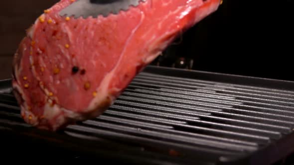 Cook Puts Steak Using Tongs on the Grill Grate alt