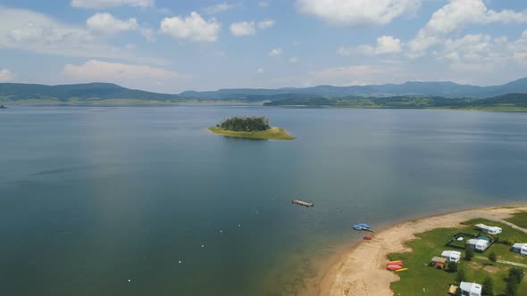 View of Lake Island and Lake Shore with Cloudy Sky in The Background alt