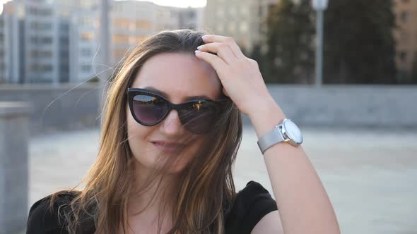 Portrait of Young Businesswoman in Sunglasses with Cityscape at Background alt