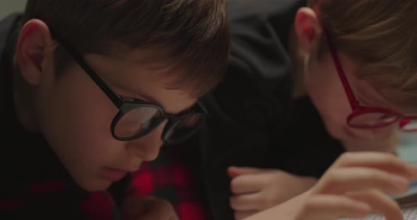 Siblings in Eye Glasses Reading Paper Book alt