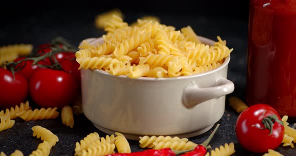 Bowl with Dry Pasta Fusilli with Tomatoes Slowly Rotates alt