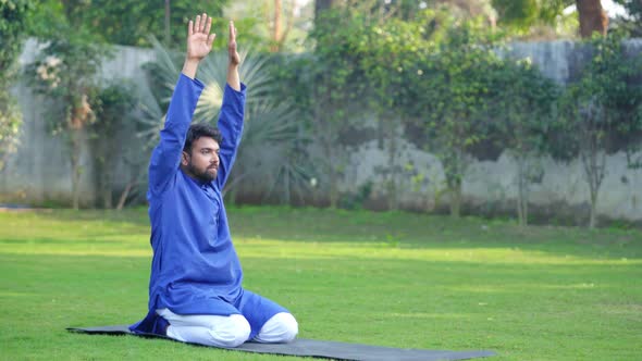 Indian man doing Extended Child Yoga Pose or Prasarita Balasana in an Indian traditional outfit alt